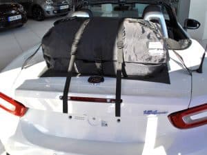 white fiat 124 spider with a boot-bag boot rack fitted hood down on a sunny day in a fiat dealership