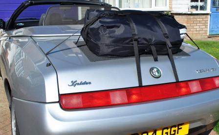 silver alfa romeo spider 916 with the hood down and a boot-bag original luggage rack fitted on a sunny day