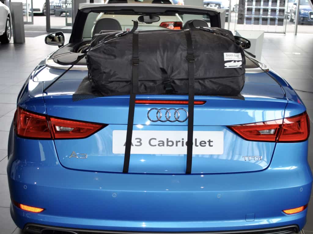 blue audi a3 convertible with a boot-bag original luggage rack fitted photographed from behind in an audi showroom