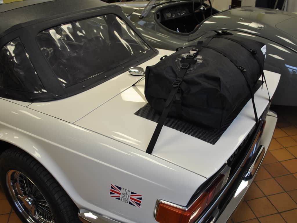 white triumph tr6 wth a boot-bag luggage rack fitted in a classic car dealership