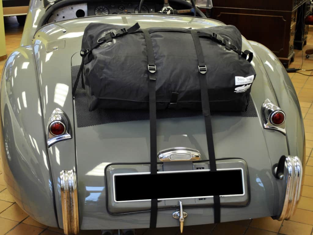 light grey jaguar xk120 with the roof off and a boot-bag luggage rack fitted