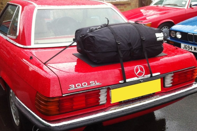 red mercedes benz 300sl in the rain with a hardtop fitted and a boot-bag luggage rack fitted to the boot