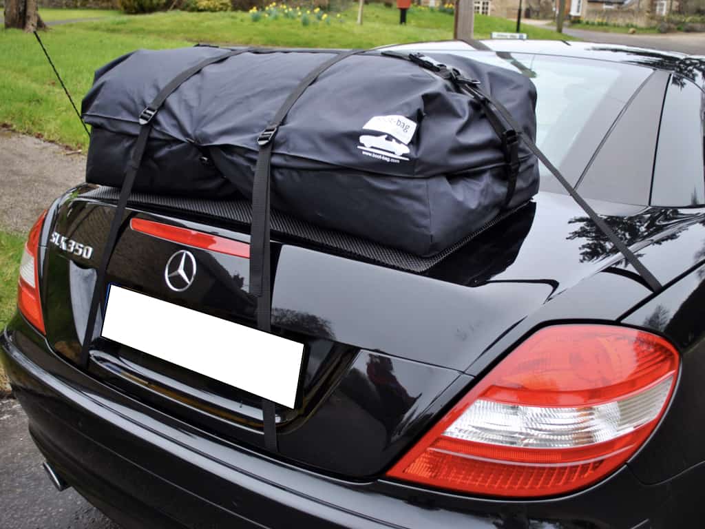 black mercedes slk 350 R171 with a boot-bag vacation luggage bag fitted in a village next to the green