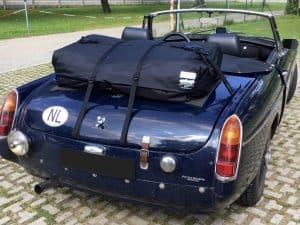 dark blue mgb with the hood down and a black interior and black wire wheels parked up with a boot-bag vacation luggage rack fitted