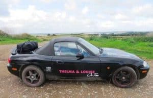black mazda mx5 mk2 with the hood up and a boot-bag boot rack fitted