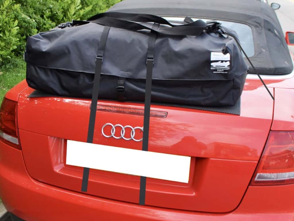red audi a4 convertible with a boot-bag luggage rack fitted photographed close from behind next to a hedge