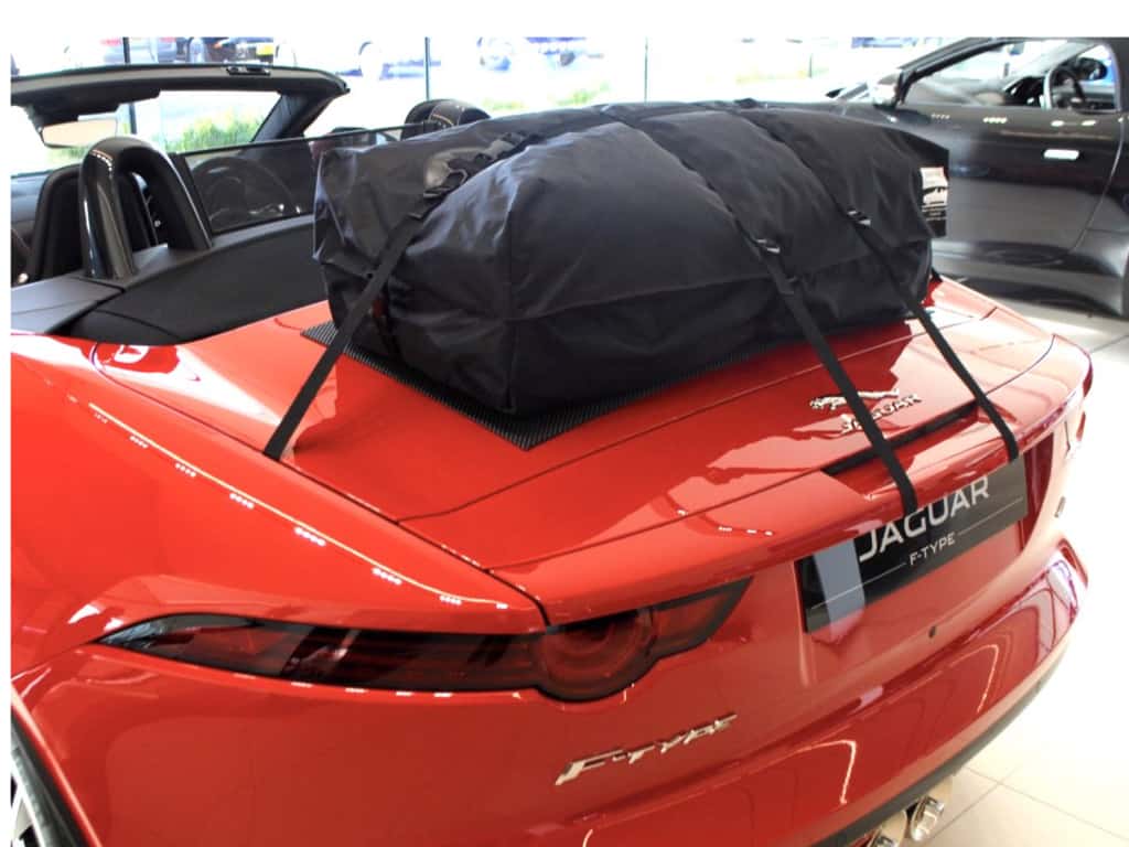 bright orange jaguar f type convertible with a boot-bag luggage rack fitted in a jaguar showroom