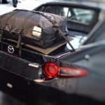 black mazda mx5 rf with a luggage rack fitted in a mazda garage