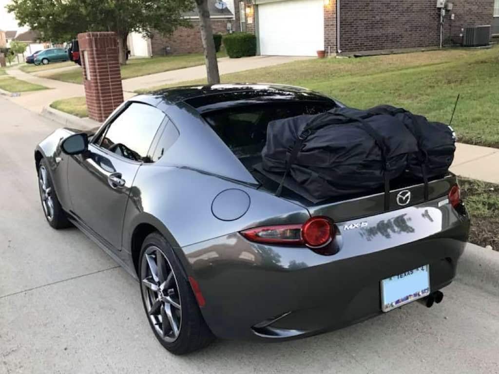 Grey mazda miata rf with a boot-bag vacation luggage rack fitted outside a house in texas