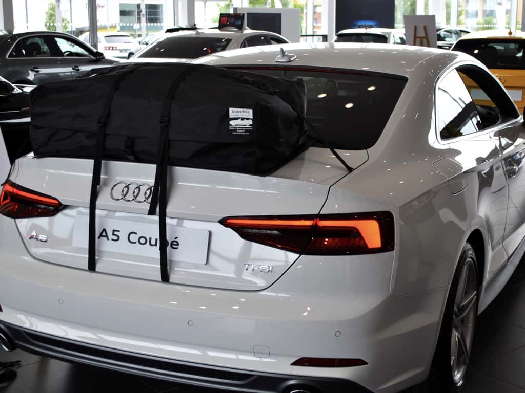 white audi a5 coupe with a boot-bag roof box fitted in an audi showroom