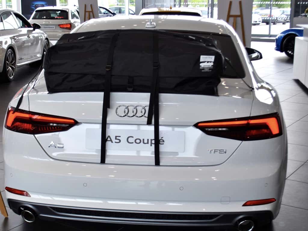 rear view of a white audi a5 coupe with a boot-bag roof box fitted