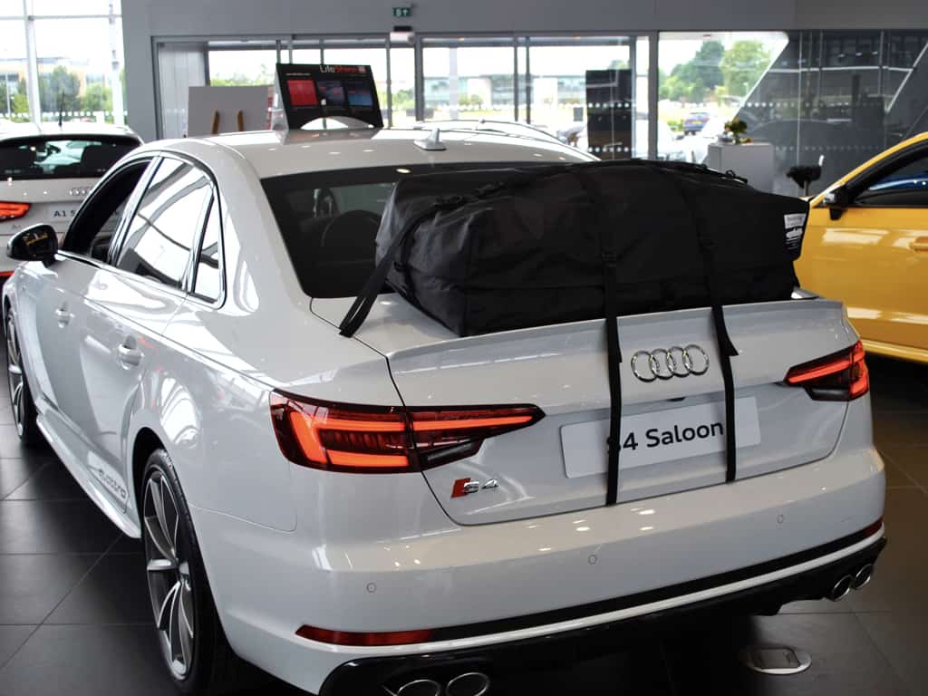 white audi a4 saloon in an audi garage with a boot-bag roof box fitted
