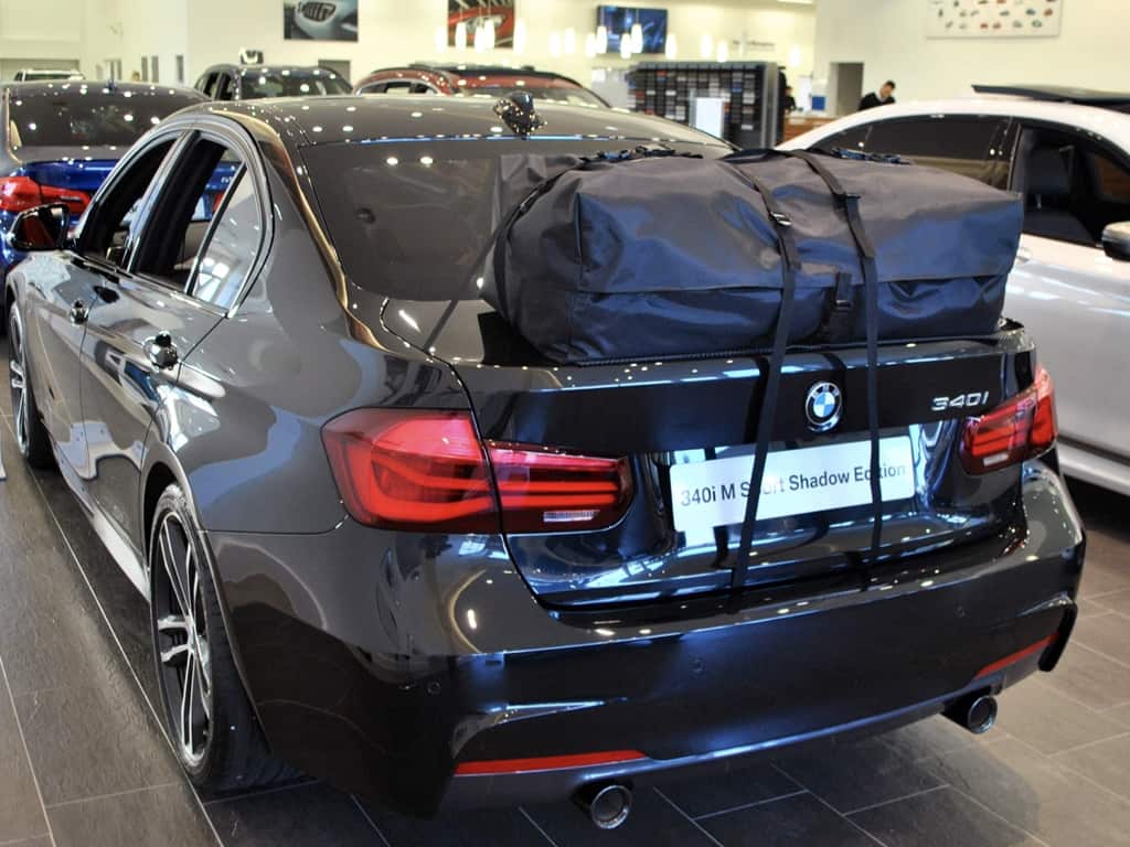 grey bmw 340i saloon in a bmw dealership with a boot-bag roof box fitted