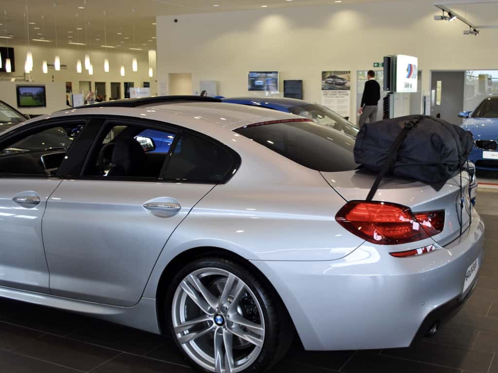 side view of a bmw 6 series gran coupe with a boot-bag vacation roof box fitted in a bmw showroom