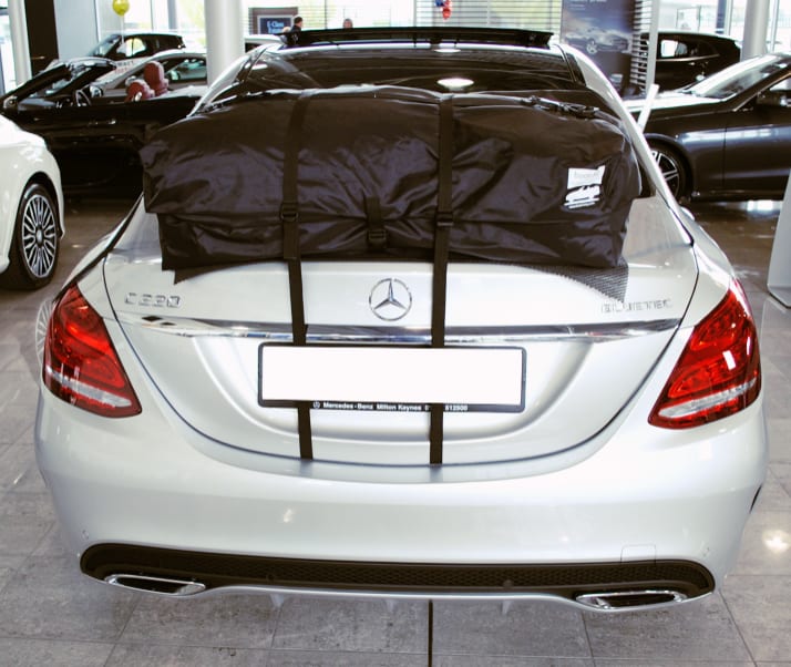 rear view of a mercedes benz c class with a black roof box fitted in a mercedes showroom