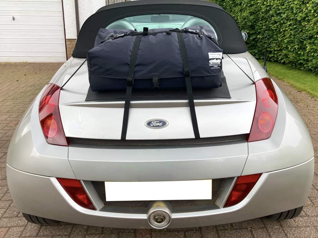 silver Ford KA Street KA convertible with a luggage rack fitted photographed from the rear on a driveway next to a hedge