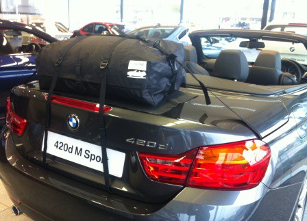 grey bmw 420d convertible with the roof down and a bootbag luggage rack fitted