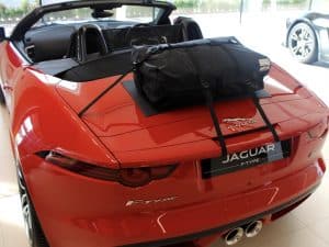 orange jaguar f type cabriolet with a boot-bag original luggage rack fitted roof down in a Jaguar showroom