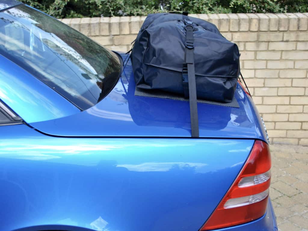 side view of a mercedes benz slk in blue with a boot-bag luggage rack fitted next to a wall 