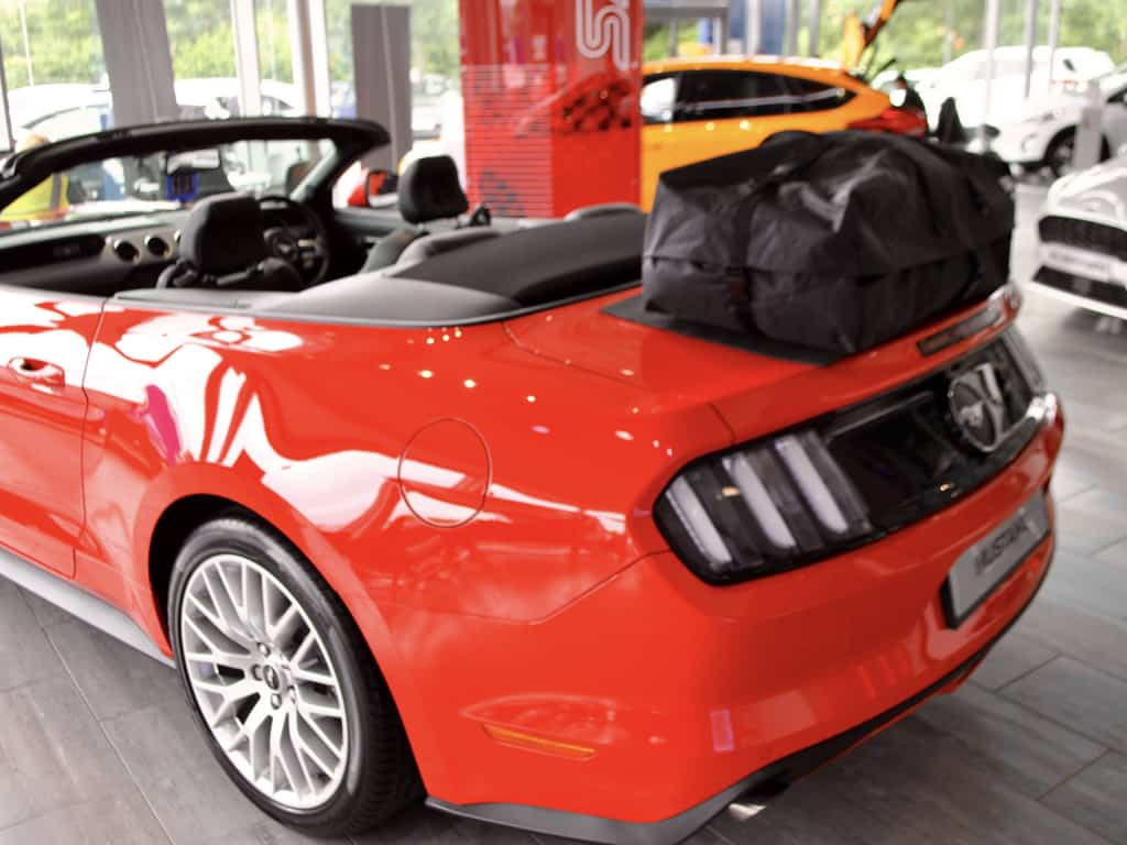 red 6th generation ford mustang convertible with a boot-bag vacation luggage rack fitted in a ford dealership