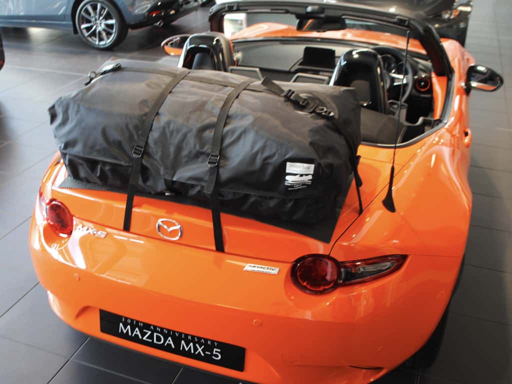 orange mazda mx5 nd mk4 with a boot-bag luggage rack fitted photographed from above in a mazda showroom hood down
