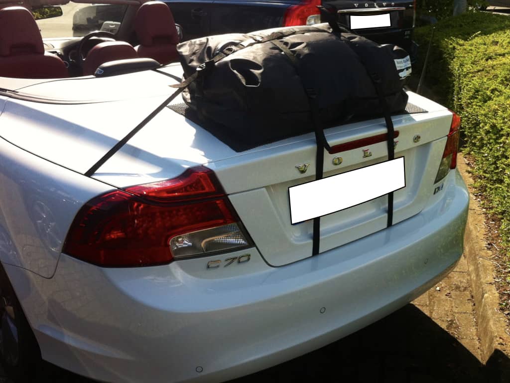 white c70 volvo convertible with a boot-bag original luggage rack fitted on a sunny day outside at a volvo dealership