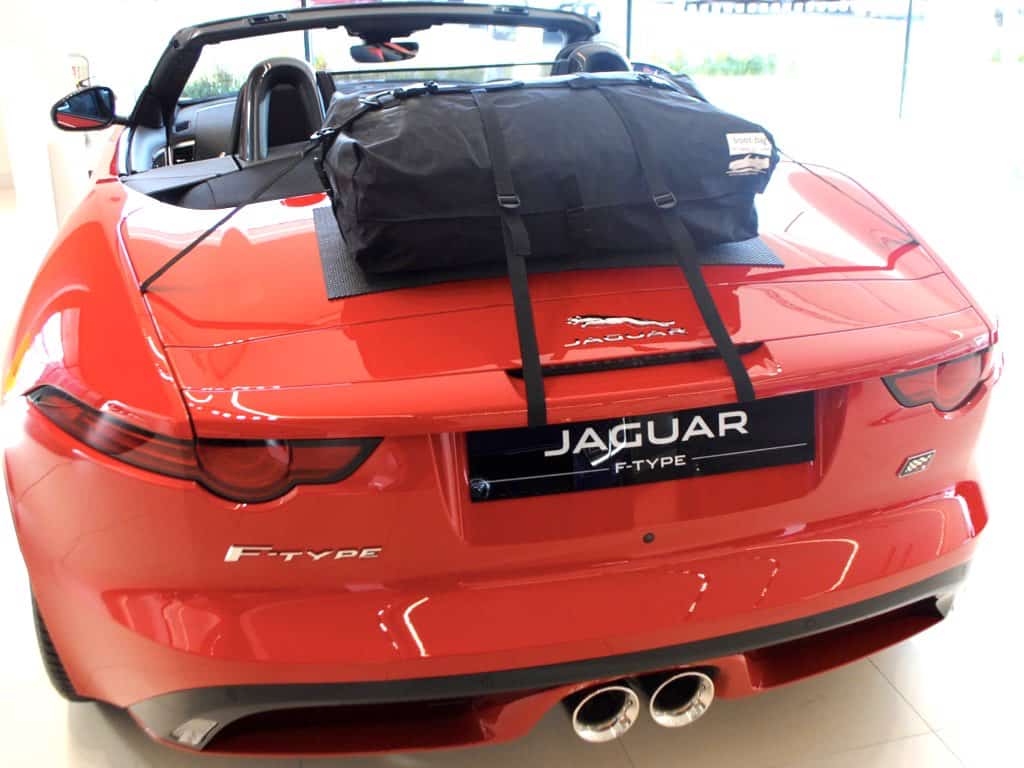 jaguar f type convertible in a jaguar showroom hood down in orange with a luggage rack fitted