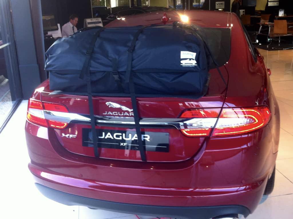 rear view of a burgundy Jaguar XF with a roof box fitted in a Jaguar garage