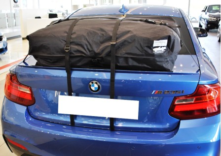 blue bmw 2 series gran coupe with a roof box fitted in a bmw garage