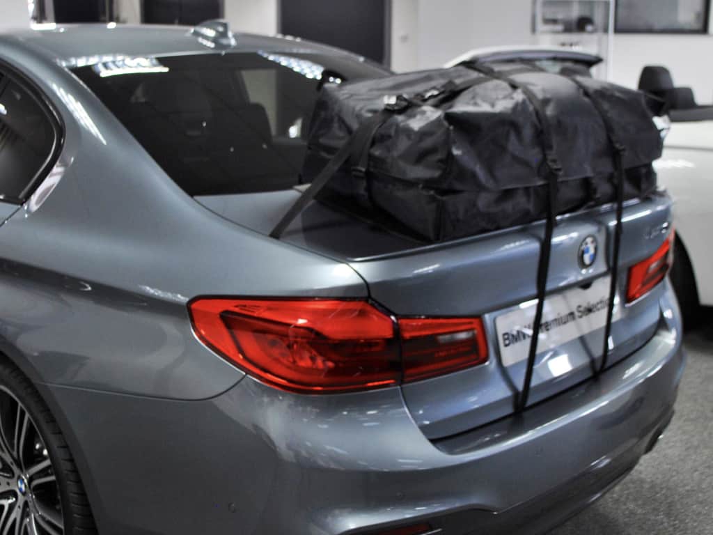 grey bmw saloon 5 series in a bmw showroom with a boot-bag roof box fitted