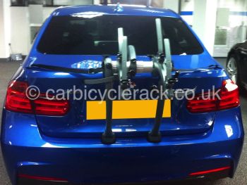 Blue BMW 3 series saloon with bike rack fitted shown from behind in BMW showroom