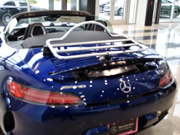 Mercedes AMG gtc descapotable azul en un showroom de Mercedes Benz con un portaequipajes de acero inoxidable instalado.