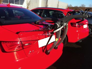 Red Audi A3 berlina con un portabiciclette montato all'esterno di un garage Audi