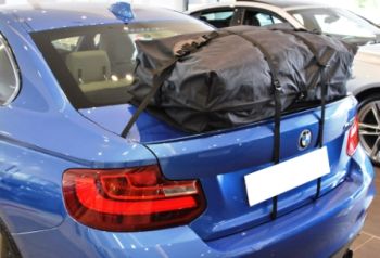blu bmw serie 2 coupé m235i con un box da tetto per le vacanze con borsa per bagagliaio montato sul cofano del bagagliaio