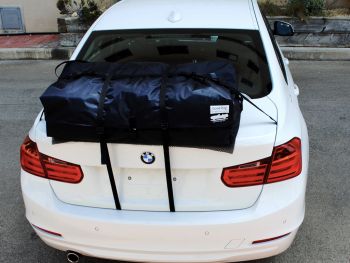 Berlina BMW serie 3 bianca con un'alternativa al portapacchi Boot-bag montata sul cofano del bagagliaio