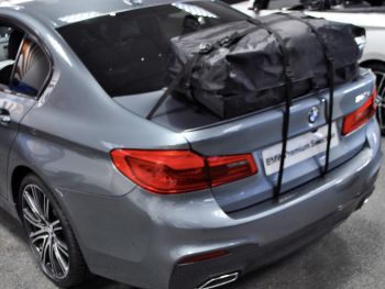 Graue BMW 5er Limousine in einem BMW-Händler mit Kofferraum-Dachbox / Dachträger montiert 