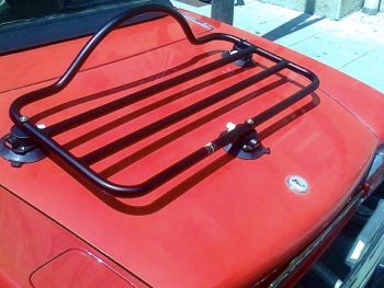 classic / oldtimer fiat 124 spider in rot mit einem schwarzen revo-rack gepäckträger in italien an einem sonnigen tag