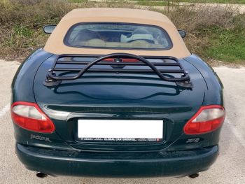 Green Jaguar xk8 with a tan roof and a black luggage rack fitted photographed from behind