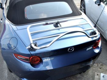 blauwe mazda mx5 nd buiten een mazda showroom met een RVS bagagerek gemonteerd