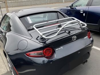 grey mazda mx5 miata rf with a chrome luggage rack fitted photographed close at the rear outside a mazda dealership