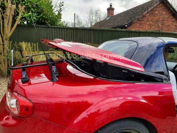 Burgundy mazda mx5 folding hard top metal roof with the roof operating and a luggage rack fitted 