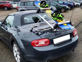 Mazda Miata with a luggage rack fitted with skis and a snowboard on it