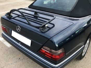 Dunkelgrünes Mercedes-Benz A124 W124 Cabriolet mit eingebautem Revo-Rack PA-Gepäckträger aus Edelstahl, nah von hinten auf einem Parkplatz fotografiert