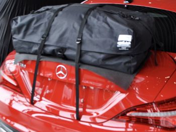 Mercedes benz cla berlina rossa con un portabagagli da tetto per le vacanze montato in uno showroom mercedes