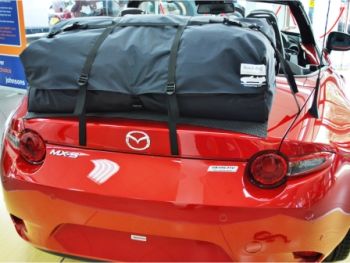 Red mazda mx5 nd miata in a mazda showroom with a boot-bag vacation luggage rack fitted photographed close from the rear 