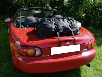 czerwona Mazda MX5 NB z oryginalnym bagażnikiem na bagaż zamontowanym przed żywopłotem