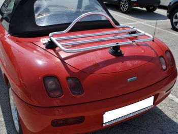 Fiat barchetta rossa con portapacchi in acciaio inox montato in un parcheggio in una giornata di sole